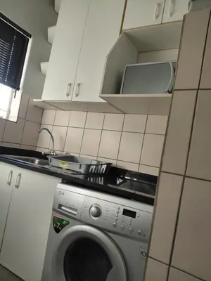 a kitchen with a washing machine in a kitchen at Shalom self catering Cottage in Centurion