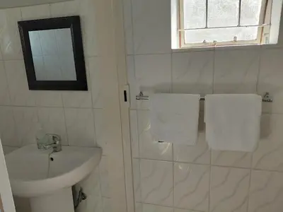 a bathroom with a sink and a shower with towels at Shalom self catering Cottage in Centurion