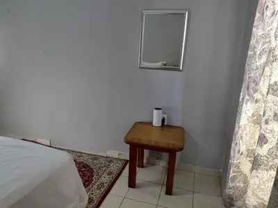 a small table in a bedroom with a bed and a mirror at Shalom self catering Cottage in Centurion