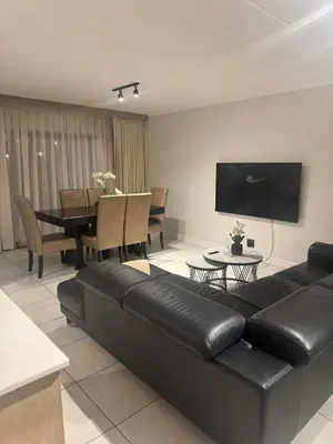 a living room with a black leather couch and a table at The Blyde Crystal lagoon 3-bed entire apartment in Pretoria
