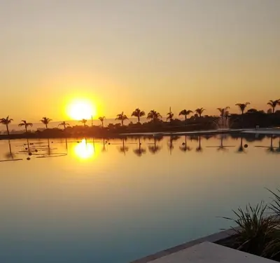 a sunset over a body of water with palm trees at The Blyde Crystal lagoon 3-bed entire apartment in Pretoria