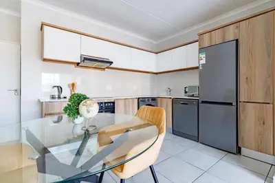 a kitchen with a glass table and a refrigerator at Crystal Lagoon lifestyle holiday in Pretoria
