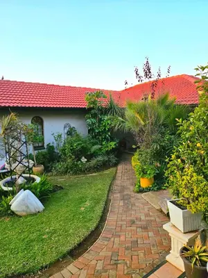 a brick path leading to a house with a red roof at The Garden on Hartbeespoort in Hartbeespoort