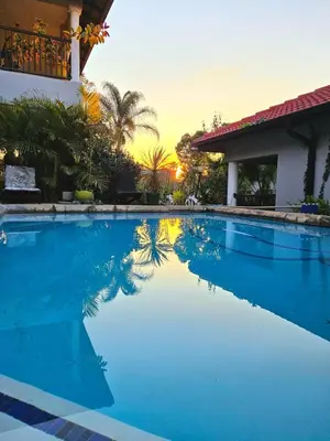 a swimming pool in front of a house with a sunset at The Garden on Hartbeespoort in Hartbeespoort