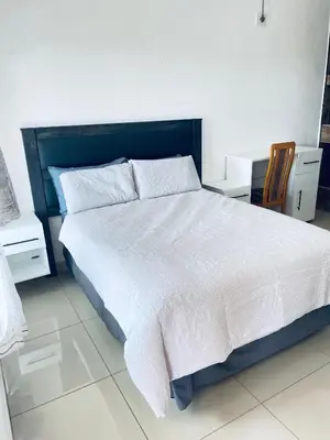 a bedroom with a large white bed and two chairs at De Mose Family Lodge in KwaZibukwane