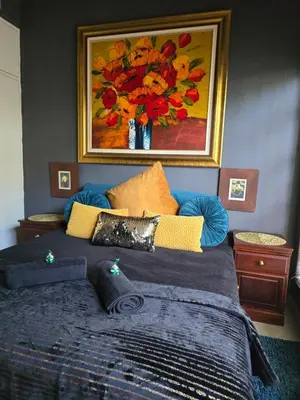 a bedroom with a bed with a painting on the wall at Sunset View in Pretoria