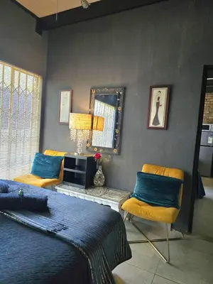 a bedroom with a bed and two chairs and a mirror at Sunset View in Pretoria