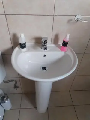 a white bathroom sink with two soap bottles on it at Wampi guesthouse in Polokwane