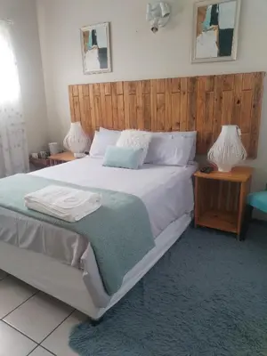 a bedroom with a large bed with two night stands at Wampi guesthouse in Polokwane