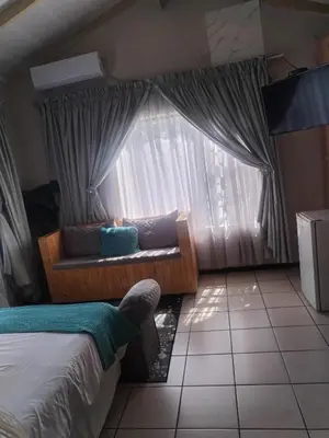 a bedroom with a couch in front of a window at Wampi guesthouse in Polokwane