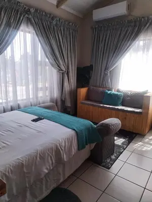 a bedroom with a bed and a couch and windows at Wampi guesthouse in Polokwane