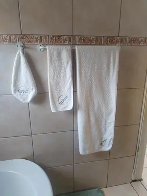 three towels hanging on a wall in a bathroom at Wampi guesthouse in Polokwane