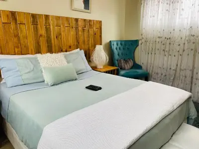 a bedroom with a large white bed and a blue chair at Wampi guesthouse in Polokwane