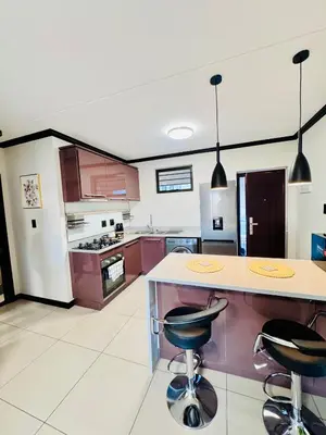 a kitchen with a counter and two bar stools at Luxury Lakeview Stay With Workspace in Midrand