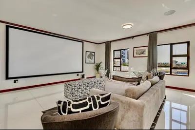 a living room with a couch and a large screen at Luxury Lakeview Stay With Workspace in Midrand