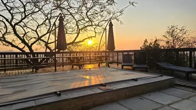 a wooden table with two chairs and umbrellas at sunset at Shiloh in Nelspruit