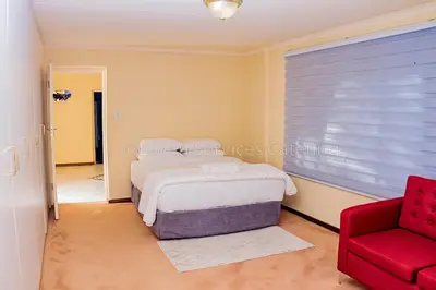 a bedroom with a bed and a red chair at No 24 Allan Road in Midrand