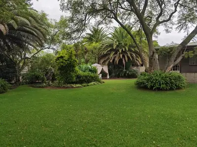 a yard with green grass and trees and a house at No 24 Allan Road in Midrand