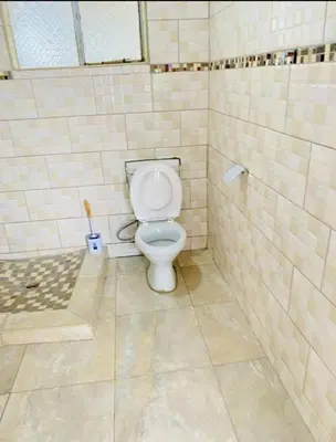 a bathroom with a toilet in a tiled stall at Mulwela Palace & Resort in Sigande