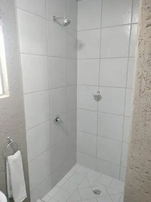 a bathroom with a shower with white tile at Mantsho Lagoon