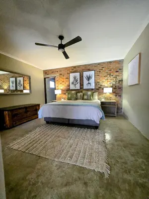a bedroom with a bed and a ceiling fan at Home with Thelana in Marloth Park
