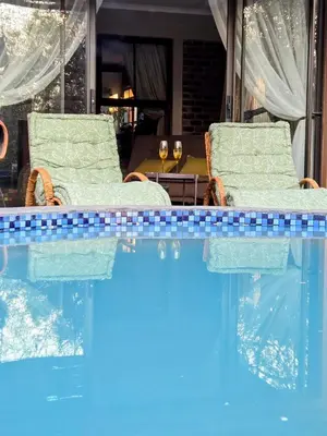a swimming pool with two chairs sitting next to a swimming pool at Home with Thelana in Marloth Park