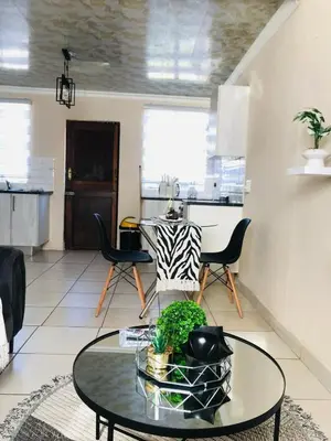 a living room with a table and a kitchen at Blanc and Bold in Vosburg