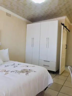 a bedroom with a bed and a white cabinet at Blanc and Bold in Vosburg