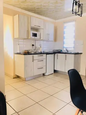 a kitchen with white cabinets and a black chair at Blanc and Bold in Vosburg