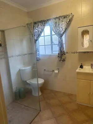 a bathroom with a toilet and a shower and a window at Klaverton Daisy in Benoni