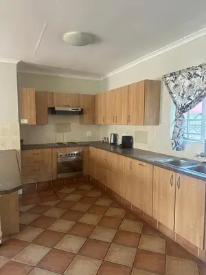 a kitchen with wooden cabinets and a tile floor at Klaverton Daisy in Benoni