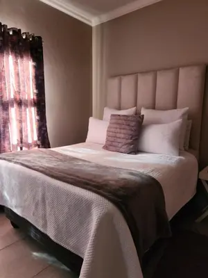 a bedroom with a large white bed with a window at Secret pillow in Trichardt