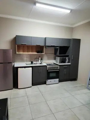 a kitchen with black cabinets and white appliances at Secret pillow in Trichardt
