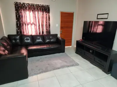 a living room with a leather couch and a flat screen tv at Secret pillow in Trichardt