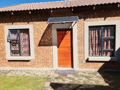 a brick house with a wooden door and two windows at Secret pillow in Trichardt