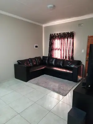 a black leather couch in a living room with a window at Secret pillow in Trichardt