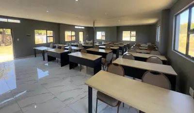 a dining room with tables and chairs and windows at Glowti Event & Guest House in Centurion