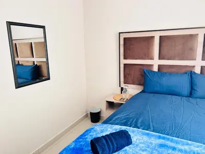 a bedroom with a blue bed and a mirror at Dubai guest house in Soshanguve