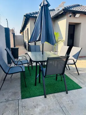 a table and chairs with an umbrella on top of grass at Dubai guest house in Soshanguve