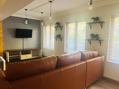 a living room with a brown couch and some windows at Big 5 Cottage in Pretoria
