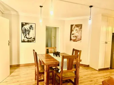 a dining room with a table and a cat sitting on the floor at Big 5 Cottage in Pretoria
