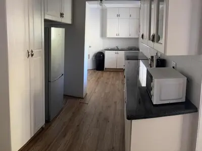 a kitchen with white cabinets and a counter with a microwave at Big 5 Cottage in Pretoria
