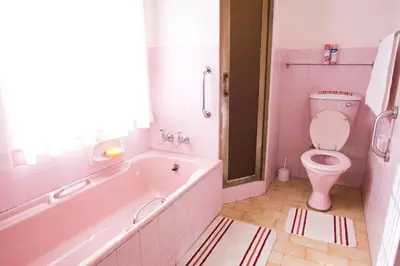 a pink bathroom with a tub and a toilet at Luisa's Place in Pretoria