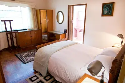 a bedroom with a bed and a bathroom with a window at Luisa's Place in Pretoria