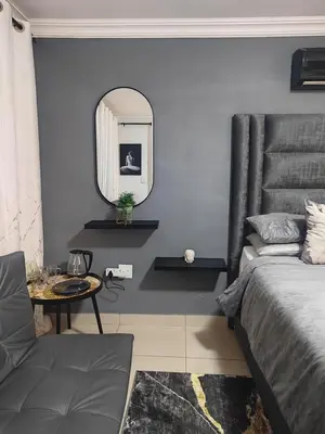 a bedroom with a bed and a mirror and a table at Palma Royal Ensuite in Pretoria