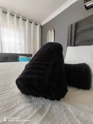 a black blanket laying on top of a bed at Palma Royal Ensuite in Pretoria