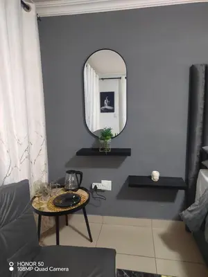 a living room with a table and a mirror at Palma Royal Ensuite in Pretoria