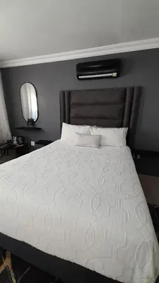a bedroom with a large bed with a white comforter at Palma Royal Ensuite in Pretoria