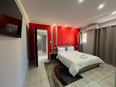 a bedroom with a bed with a red wall at 419 Guest House in Midrand