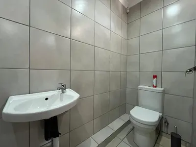 a white bathroom with a toilet and a sink at 419 Guest House in Midrand